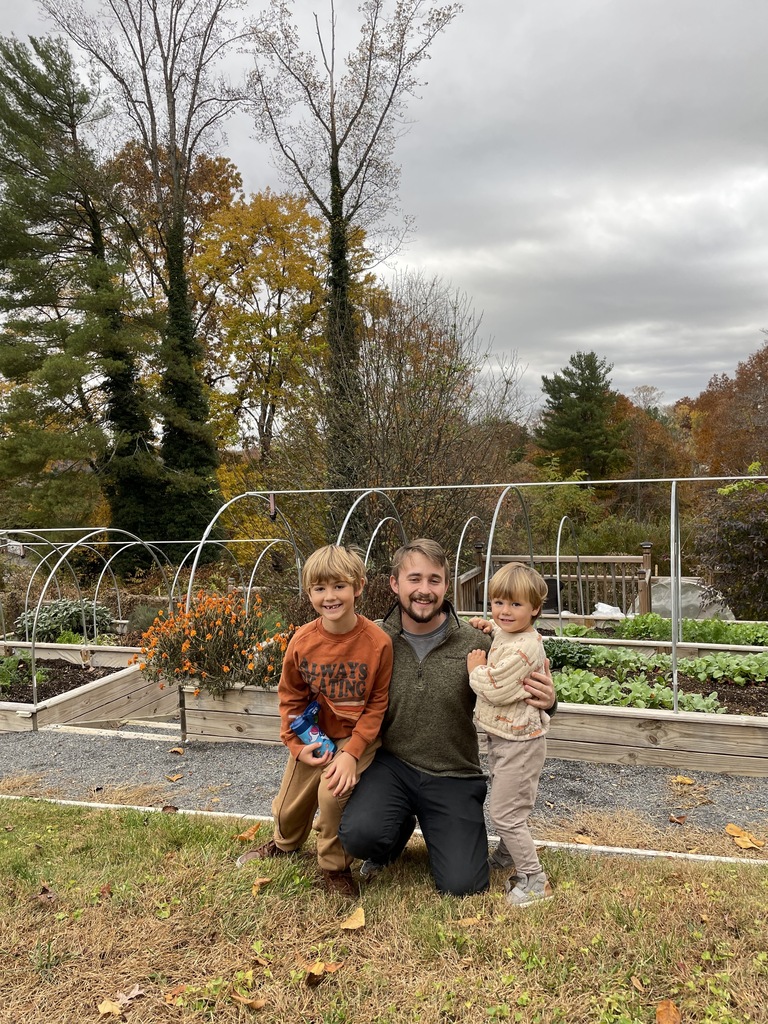 Noah kneeling between his two nephews in a garden, all three smiling